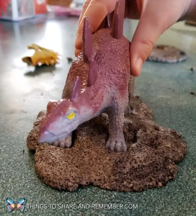 pressing dinosaur into play dough