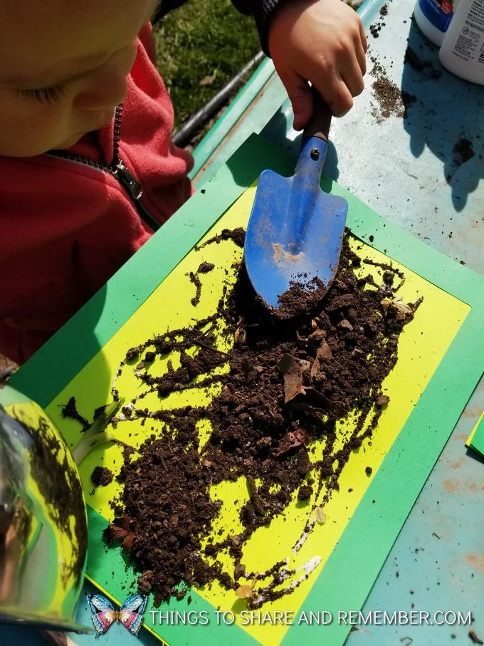 child spreading soil on green paper art