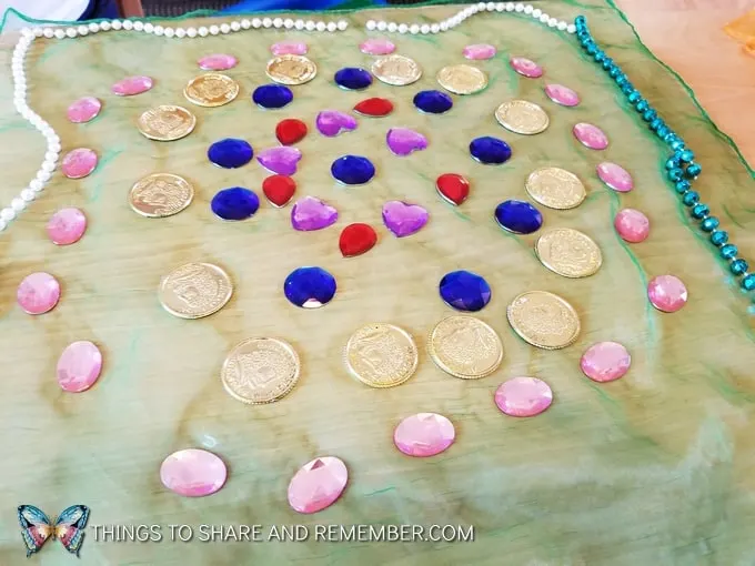using beads, gems, and plastic coins on scarves in loose parts play