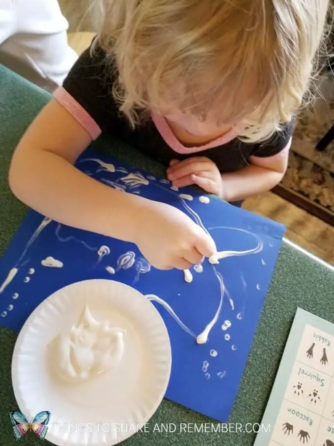 Animal Tracks art with paint and q-tips making tracks on blue paper  from Mother Goose Time Sights and Sounds #MGTblogger #MotherGooseTime #preschool #SightsandSounds 