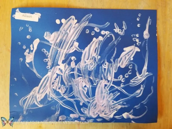 Animal Tracks art with paint and q-tips making tracks on blue paper from Mother Goose Time Sights and Sounds #MGTblogger #MotherGooseTime #preschool #SightsandSounds