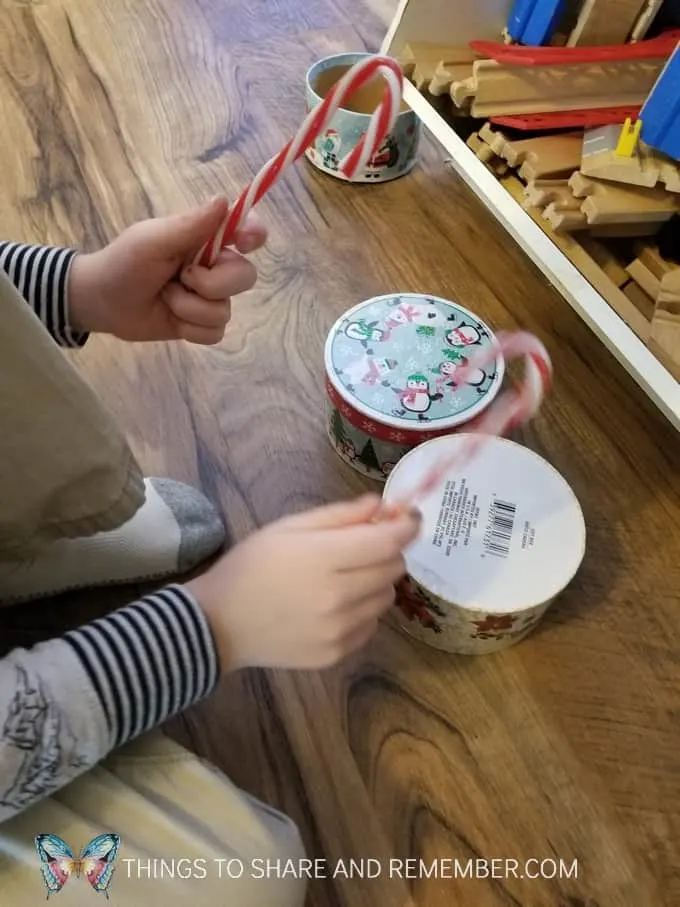 Tapping on boxes with plastic candy canes to create his own unique drum and sound. #MGTblogger #MotherGooseTime #preschool #SightsandSounds