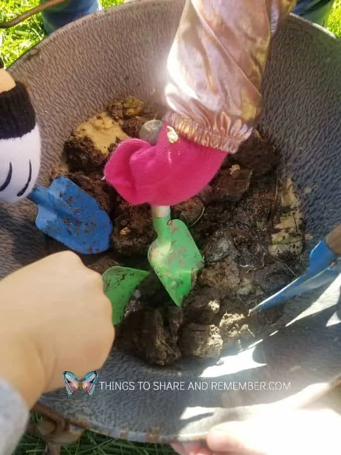 Nature Play Mud Pies mixing dirt and water in a bucket | Experience Preschool Down on the Farm theme