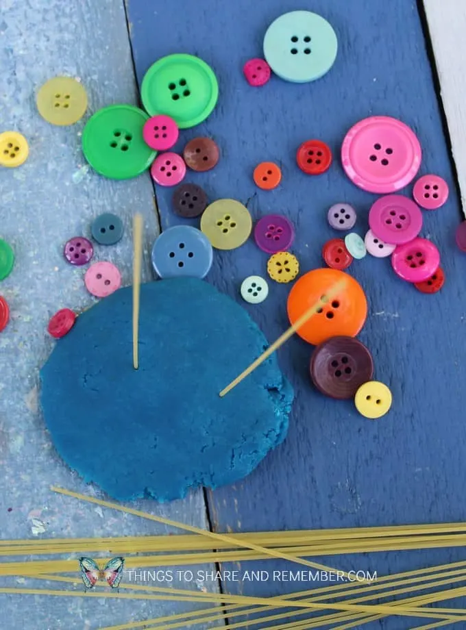 spaghetti noodles in play dough for threading buttons