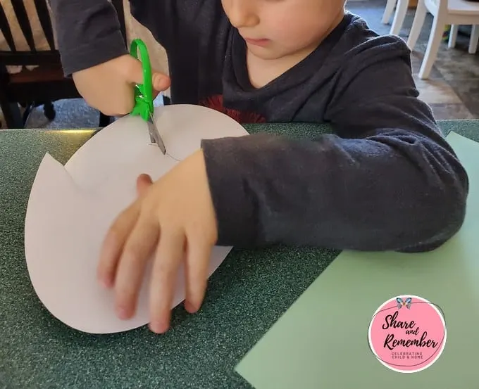 Preschooler cutting paper egg.