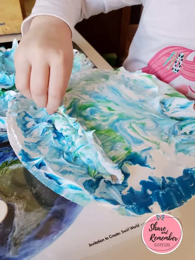 Child scraping shaving cream off paper plate.