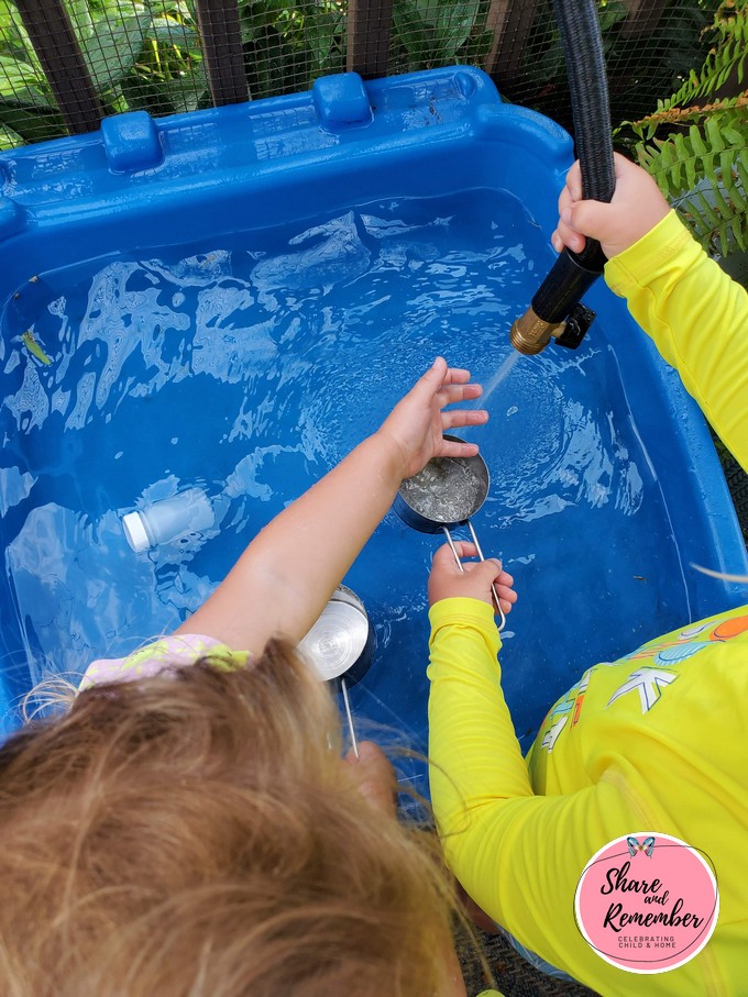 kids playing with water table and hose