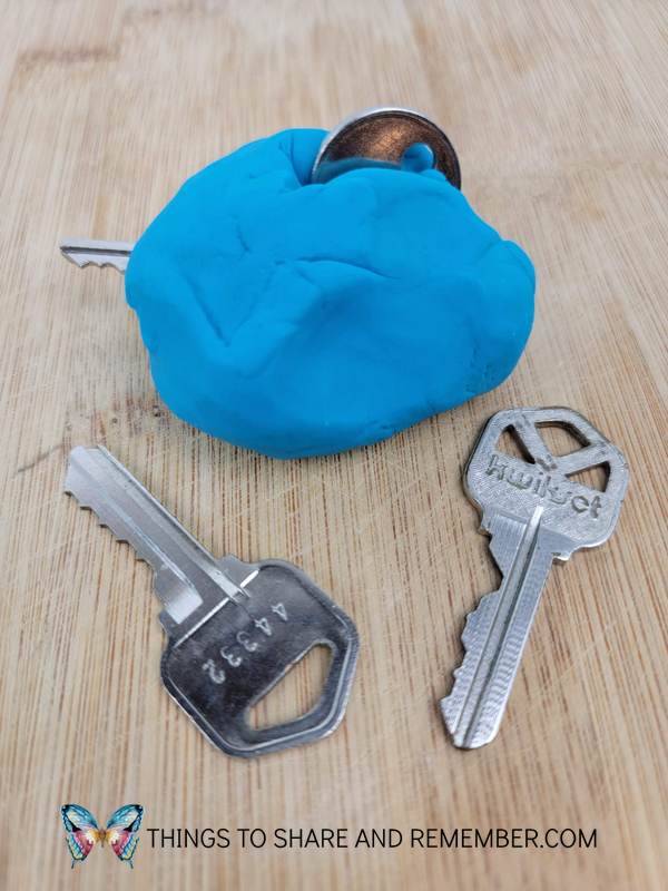 lump of blue playdough with keys hidden inside for a toddler to find and dig out developing fine motor skills