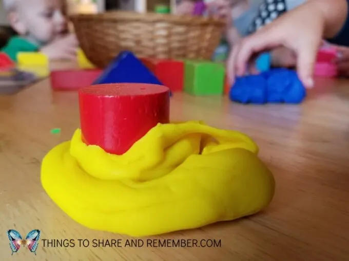 round red block pushed into yellow playdough